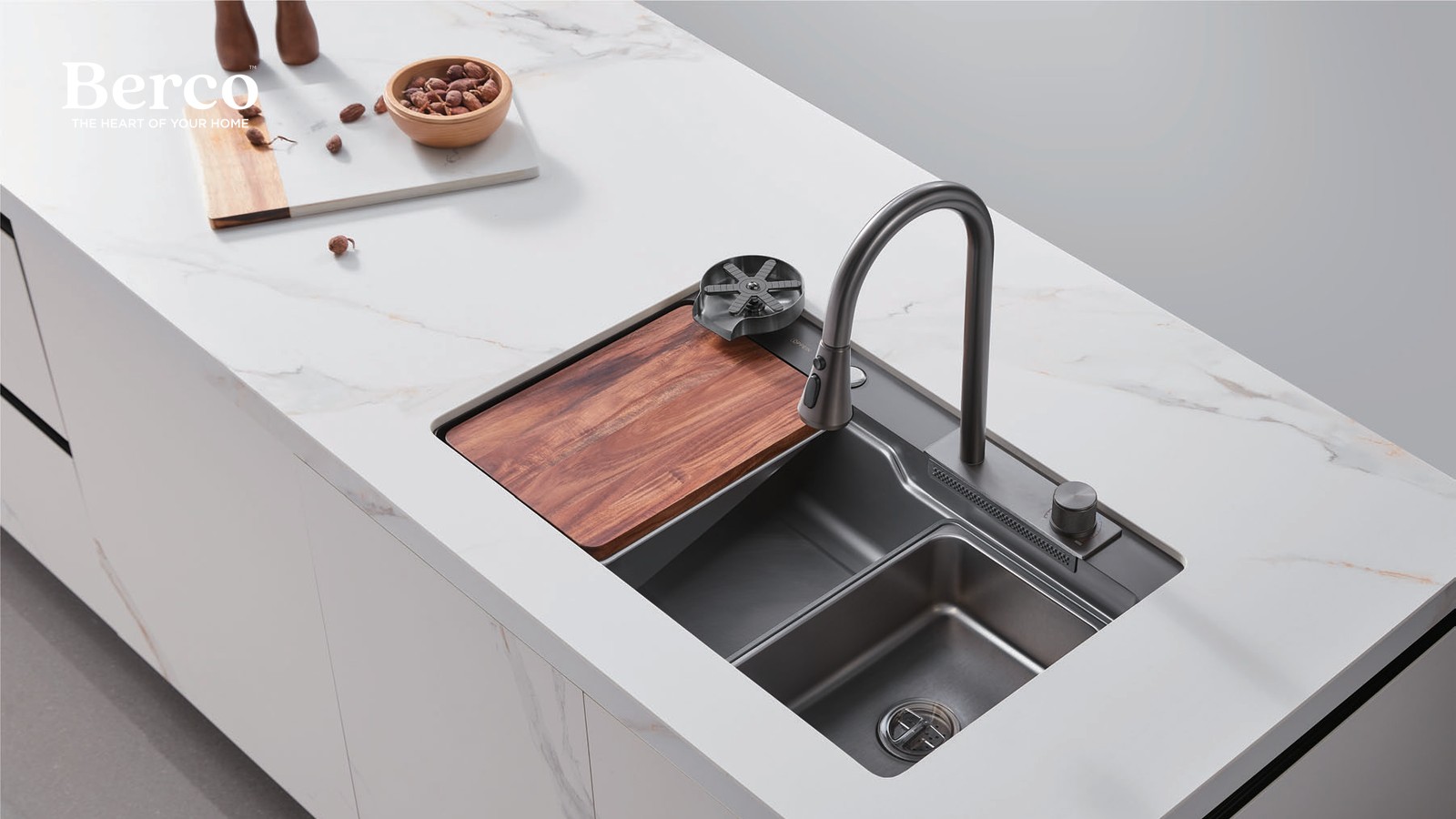 A stainless workstation sink set into a stone island top with a sliding timber board, strainer accessory and pull-down tap — Berco design reference.