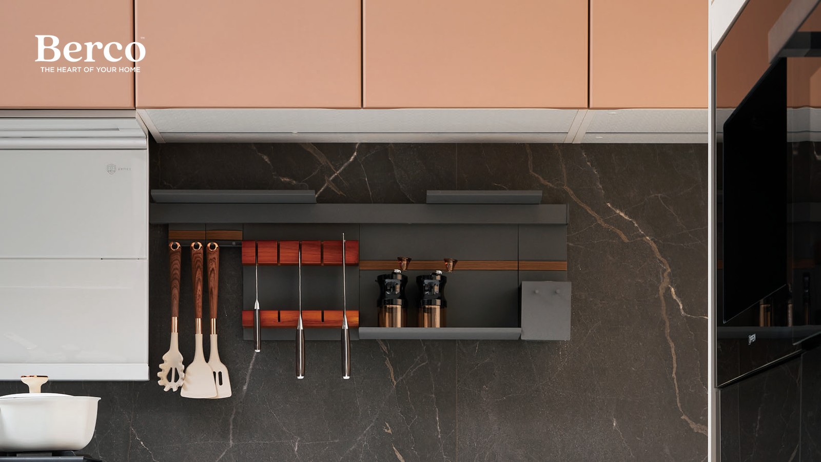 A wall rail system on a dark stone splashback holding hanging utensils, a timber knife rack and a short shelf of grinders — Berco design reference.