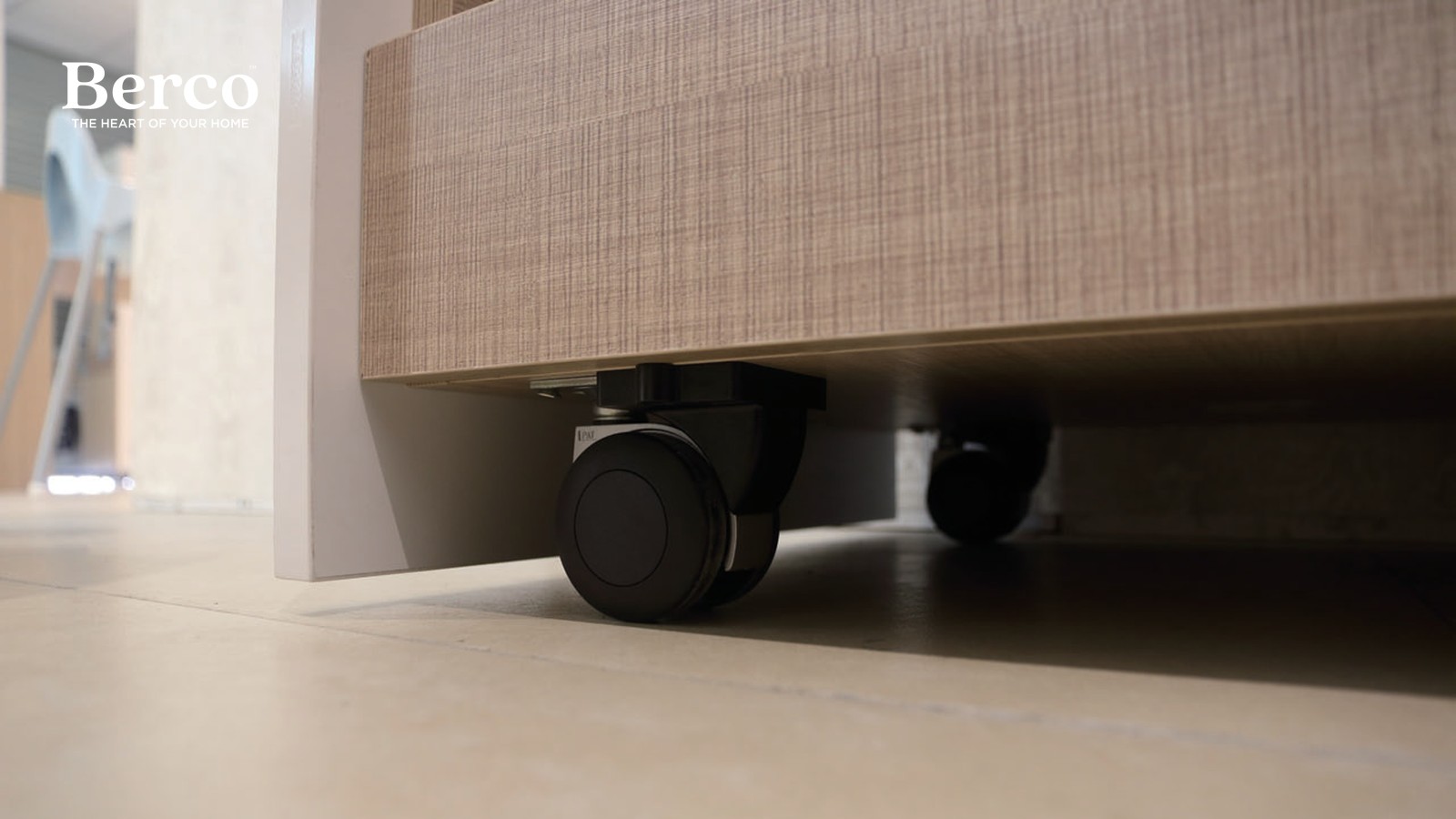 A close view of concealed castors under a textured cabinet base, letting the unit roll clear of its bay — Berco design reference.